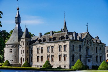 Boussu-en-Fagne kalesi açık mavi gökyüzüne, gri taş duvarlara, gable çatıya, konik kubbeli ve çoklu pencereli yuvarlak kuleye, güneşli yaz gününe karşı Couvin, Namur, Wallonia, Belçika