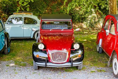 İyi korunmuş kırmızı kaportalı klasik araba. Üstü yumuşak, dikiz aynası, far, krom metal detaylar, Belçika 'da güneşli bir yaz günü.