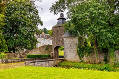 Acoz Kalesi 'nin ana girişinde küçük bir köprü, gri konik çatıları olan kireçtaşı kuleler ve arka planda binanın bir kısmı Gerpinnes, Hainaut, Wallonia, Belçika' da bulutlu bir gün.