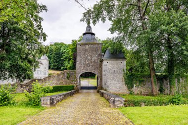 Acoz kalesinin ana girişi hendeğin üzerindeki küçük köprü arka planda gri konik çatıları olan kireçtaşı kuleler Gerpinnes, Hainaut, Wallonia, Belçika 'da bulutlu bir gün.