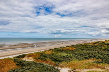 Yelkenli ya da karasal yelkenli, kumullar ve Kuzey Denizi 'ne karşı gökyüzü bulutlarla kaplı arka planda ufuk, De Panne, Batı Flanders, Belçika' da bulutlu bir gün.