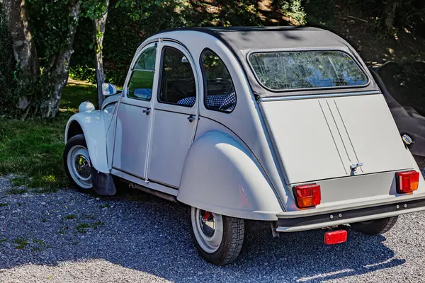 stock image Rear side view of an old convertible luxury car with soft top, grey body, rear view mirror, three red rear brake lamps, sunny summer day in Belgium