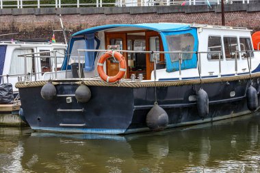 Maastricht şehrinin eski tarihi iç limanının rıhtımında asılı şamandıraları olan geminin kıç tarafı, arka planda tuğla duvar, Güney Limburg, Hollanda 'da bulutlu bir gün.