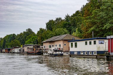 Maastricht şehrinin dışındaki nakliye kanalı boyunca kıyıda yüzen yüzen yüzen yüzen tekneler, arka planda yapraklı ağaçlar, Güney Limburg, Hollanda 'da bulutlu bir gün.