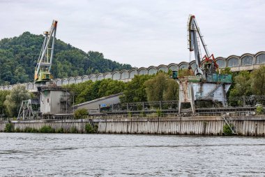 Meuse nehri kıyısındaki terk edilmiş fabrika fabrikasının dev vinçleri, yükleme ve boşaltma için kullanılır, Maastricht, Güney Limburg, Hollanda 'da bulutlu bir gün