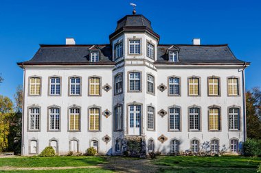 Klasik tarzda Zweibruggen Kalesi, birden fazla pencereli beyaz duvarlar, altıgen kubbeli gablı merkez kule, harap olmuş ana merdiven, ön manzara, Ubach-Palenberg, Almanya