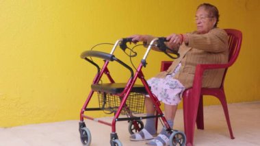 Yaşlı kadın ayağa kalktı ve yürümeye başladı, kırmızı sandalyeye oturdu, yürüyerek bacaklarını çalıştırdı. Engelli insanların günlük yaşamlarını kolaylaştıracak nesneler kavramı