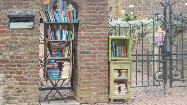 Itteren, Maastricht, Hollanda. 29 Eylül 2024. Açık hava halk kütüphanesi ya da köy caddesindeki konutun duvarındaki entellektüel duruş, okumak ve kültür yaratmak için ücretsiz kitaplar.