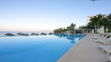 Sahildeki tatil köyü yüzme havuzunun panoramik görüntüleri, şezlonglar, palapalar plajda, ufukta ve Pasifik Okyanusunda, Meksika Nuevo Vallarta 'da sakin bir sabah.