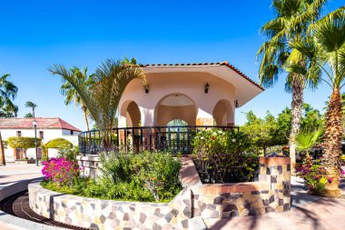 Meksika 'nın merkez meydanında büfe, taş duvar, metal korkuluk, tropik palmiye ağaçları, arka planda binalar, Loreto, Baja California Sur, Meksika' da mavi gökyüzü ile güneşli bir gün.