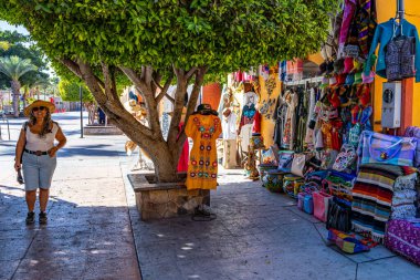 Çeşitli hediyelik eşya satan yaya sokakları, gülümseyen kadın turistler, geleneksel Meksika elbiseleri, çantalar, el sanatları, Loreto 'da güneşli bir gün, Baja California Sur, Meksika