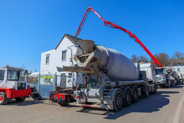 Birkaç beton karıştırıcı kamyon inşaat alanına çimento, arka planda beton hortumlu vinç, Gulpen, Güney Limburg, Hollanda 'da güneşli bir gün.