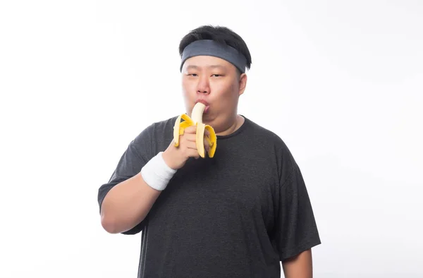 Mladý Asijský Legrační Tlustý Sportovní Muž Jíst Banán Izolované Bílém — Stock fotografie