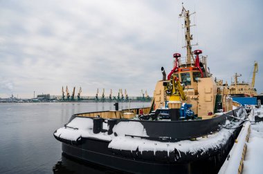 Karlı kış mevsiminde sanayi limanı, ön planda gemiler