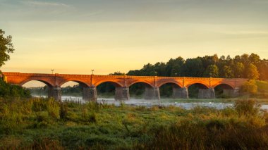 Venta nehri üzerindeki taş köprü Avrupa 'nın en geniş şelalesinin yanında Rumba Kuldiga, Letonya' da sonbaharda gündoğumunda