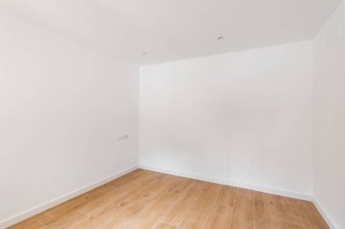 Empty room with laminate flooring and newly painted white wall in refurbished apartment. Repair and construction concept