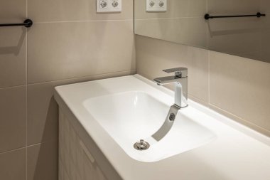 Bej kaplamalı lüks banyoda yepyeni bir musluk. Detaylı olarak modern iç mekan