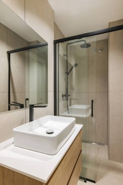 Yenilenmiş dairede modern tarz banyo. Duş alanı, siyah musluk ve aynayla batmak.