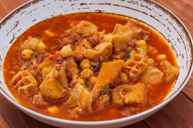 Ration of tripe Madrid style on rustic plate on a wooden table. Callos a la Madrilena - typical spanish dish. clipart