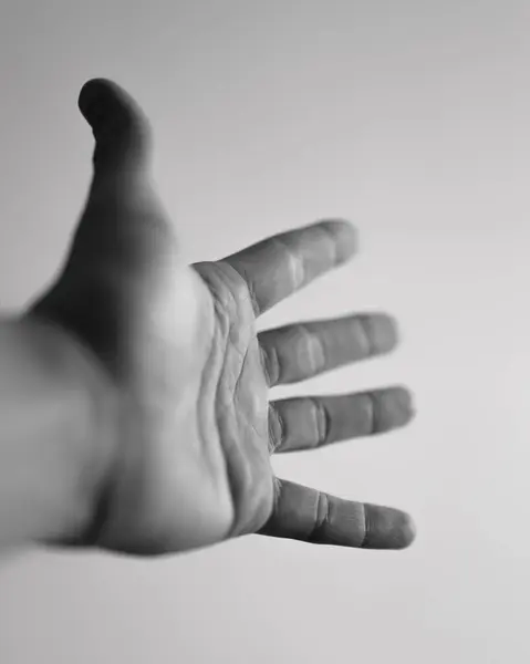 A human hand reaching out with fingers extended, creating a sense of motion and perspective
