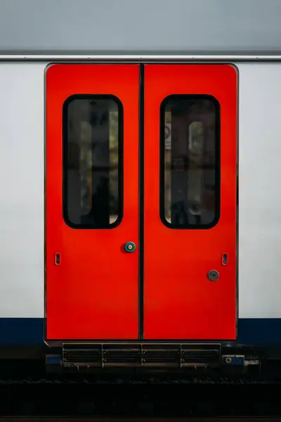 Modern technologies for opening sliding doors of an electric train car using a touch button. Closed red doors of a passenger car as part of a subway train. A vehicle for fast travel