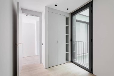 Modern stil giriş salonu iç mimarisi, ahşap ışıklı parke zeminli nötr beyaz koridor, siyah alüminyum çerçeveli kostüm ve cam kapı sokağa erişimi olan