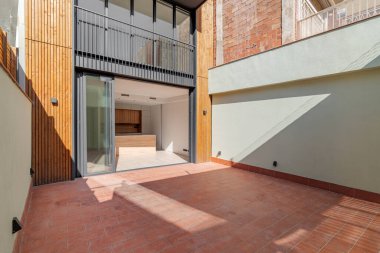 Siyah metal ve camdan yapılmış sürgülü kapıları olan birkaç katlı bir bina. Mutfağa açılan kapı hafif ahşap mobilyalarla açılıyor. Kırmızı döşemeli veranda meraklı gözlerden kapalıdır.