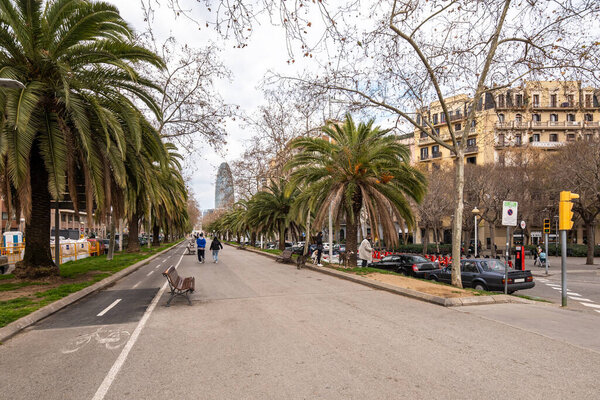 DECEMBER 19, 2022 - BARCELONA, SPAIN: wide pedestal way with markings and bicycle lane. City street with buildings, cars and people walking.