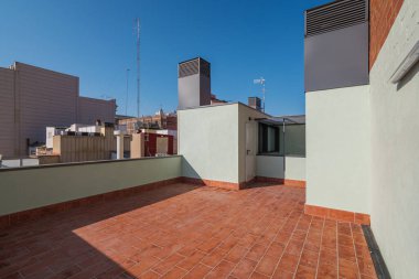 Büyük bir evin çatısında boş, ferah bir teras. Güneşin altında sıcak yaz akşamlarında dinlenmek için fayanslı kırmızı zemin var. Güneş ışığı çatıyı aydınlatır.