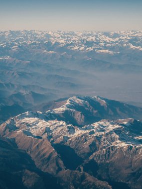 Yukarıdan Alpler 'in pürüzsüz ana hatları. Alp dağ sistemi ufuk çizgisine kadar uzanır, yamaçlar bazı yerlerde kar örtüleriyle kaplıdır, güneş ışınları bayırları aydınlatır.
