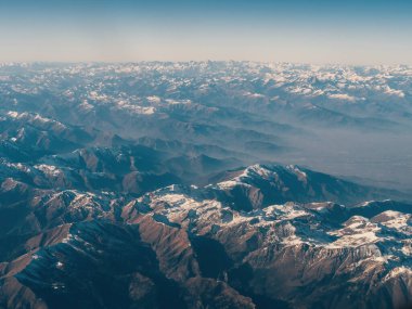Dağ Alpler sistemi ufuk çizgisine kadar uzanıyor, yamaçlar kar örtüleriyle kaplı, güneş ışınları yamaçları aydınlatıyor. Dağların düz dış hatları yukarıdan geliyor