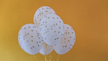 Soyut konfeti dizaynlı beyaz mat balonları. Her top şeritte tutulur ve kendi ekseni etrafında sorunsuzca döner. Tatil için güzel bir dekorasyon.