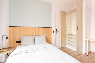 Büyük, çift kişilik yataklı, güzel çarşaflı bir otel odası. Yatak başlığının duvarında ahşap paneller var. Giysiler ve ayakkabılar için büyük bir gardırop. Kapı elektronik olarak dijital kodla kilitlenmiş.