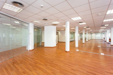 Tavan kiremitleri, floresan ışıkları, açık kahverengi lamine döşeme ve beyaz boyalı sütunları olan büyük boş bir alan. Kiralık büyük ofis yeni yenilendi ve döşenmedi..