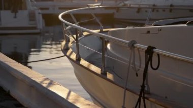 Sessiz marina sahnesi, gün ışığı tekne tarafında parlıyor, rıhtıma bağlı..