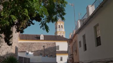 Bir kilisenin tarihi saat kulesi sessiz bir kasaba caddesinin üzerinde yükseliyor. Ağaçlar hafif esintide fısıldıyor..