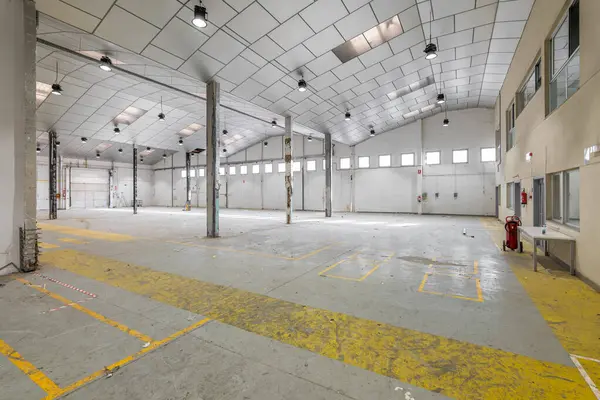 Spacious large room for a warehouse or parking with windows with metal pillars and a ceiling prepared for cosmetic repairs. The concept of business premises after reconstruction.