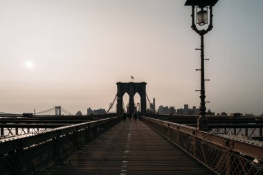 New York 'ta Brooklyn Köprüsü üzerinde sakin bir gündoğumu ve ufuk çizgisi. Sabahın erken saatlerinde sakin bir sahne ve boş bir köprü..