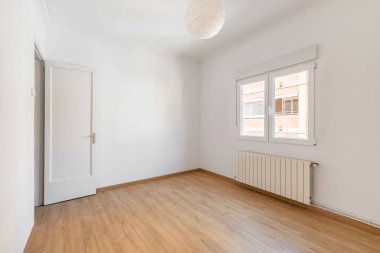 Boş beyaz oda, pencereli ve otel odasının ön kapısı ahşap kaplamalı. Tatil sırasında taşınma ya da bir otel odasında kalma fikri. Kopyalama alanı.