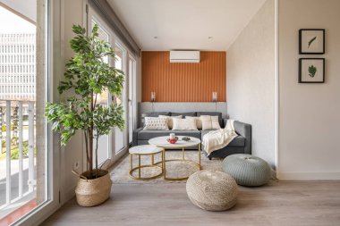 Oturma odasının panoramik pencerelerinin yanında bir kanepe ve buruşukluk olan terracotta renkli bir duvarı olan şık bir oturma odası. Modern İskandinav iç mimarisi kavramı.