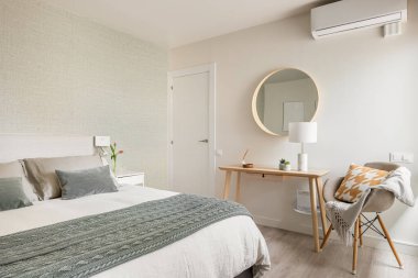 Geniş, rahat bir yatak odası, çift kişilik bir yatak odası, kozmetik masası ve içinde eko-boho tarzı bir ayna. Eski bir dairede iç dekorasyon konsepti.