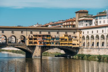 Güneşli bir yaz gününde turistlerle İtalya 'nın Floransa kentinde Arno nehrinin üzerinde kapalı lintelleri olan çarpıcı sarı renkli ortaçağ taş segmenti kemer köprüsünün manzarası. Kopyalama alanı.