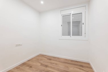 Minimalist, ahşap zeminli, beyaz duvarlı ve geniş pencereli modern bir oda temiz ve ferah bir yaşam alanı sunar.