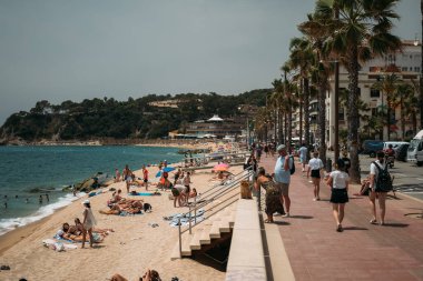 Lloret de Mar, İspanya - 24 Temmuz 2024. Costa Brava 'da neşeli kalabalıkların güneşin ve okyanusun tadını çıkardığı canlı ve canlı sahil hayatını yaşayın.