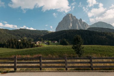 Dolomitlerin nefes kesen manzaraları yuvarlanan tarlalar ve açık mavi gökyüzünün altında yükselen tepeler.