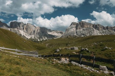 Görkemli Dolomitlerin nefes kesici manzarası yükseliyor, engebeli zirveler ve canlı yeşil otlaklar sergiliyor.