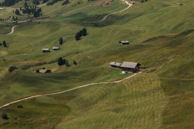 Parlak gökyüzünün altındaki yemyeşil otlaklarda yuva yapmış büyüleyici kamaraların bulunduğu güzel Dolomitler manzarası..