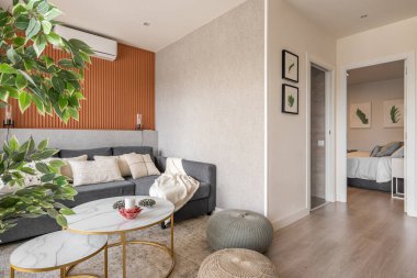 Dinlenme odası, yuvarlak kahve masası, kanepe, puf ve banyo ve yatak odasına bakan dekoratif aksesuarları olan şık bir oturma odası. Modern şehir yerleşim kompleksi kavramı.