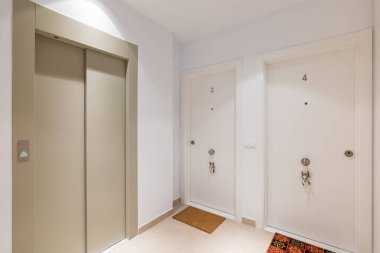 Yolcu asansörlü koridor boşluğu ve üç ve dört numaralı beyaz elbiseli otel odaları. Konforlu, modern apartman konsepti.