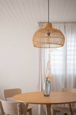 Burası güzel dokunmuş doğal kolye ışığı ve minimalist dekorasyon tarzına sahip şık bir yemek alanı.